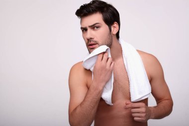 Genç ve yakışıklı bir esmer, yıkandıktan sonra yüzünü havluyla siler..