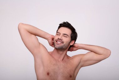 Bir adam hafif bir arka planda durur ve pürüzsüz koltuk altlarını gösterir..