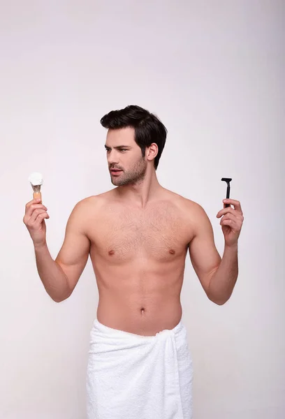 A fit young Caucasian guy shaves. — Stock Photo, Image