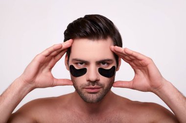 Gözlerinin altında siyah lekeler olan yakışıklı bir gencin portresi..