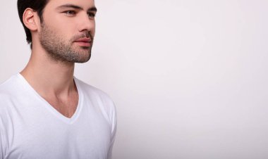 Kırpılmış çerçeve, beyaz tişörtlü yakışıklı beyaz adam yan tarafa bakıyor..