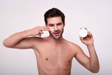 Sevimli sevimli erkek manken elleriyle yüz kremi sürüyor..