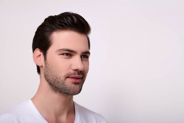 Beyaz tişörtlü gülümseyen yakışıklı bir adamın portresi..
