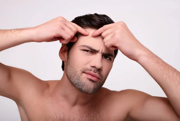 Close-up, a muscular man presses a pimple on his forehead. — Stock Photo, Image