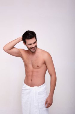 Gülümseyen zalim bir adam elleriyle başını kaşıyarak aşağı bakıyor.