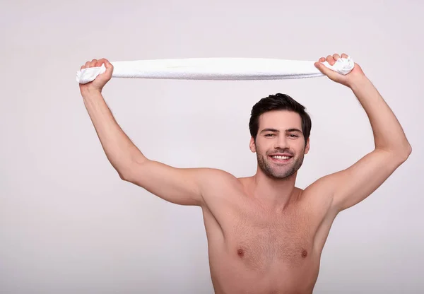 Retrato de un joven guapo desnudo con una toalla en las manos . — Foto de Stock