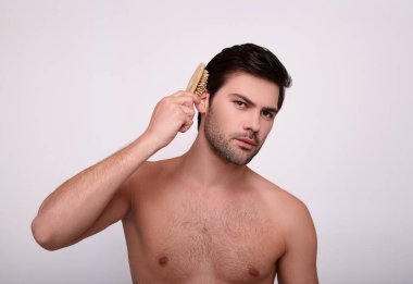 Tişörtsüz yakışıklı, seksi adam saçını tarıyor..