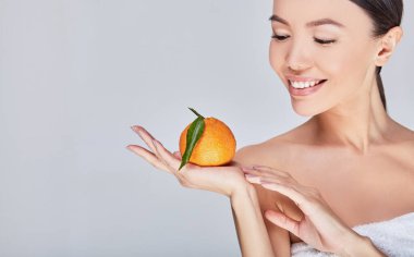 Close-up, a beautiful young Asian model smiles with citrus in her hand.