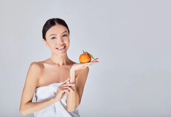 Smiling Asian girl with tangerine, orange in hand. — Stok fotoğraf