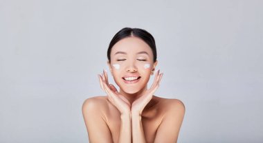 Portrait of a young Asian woman with cream on her face.