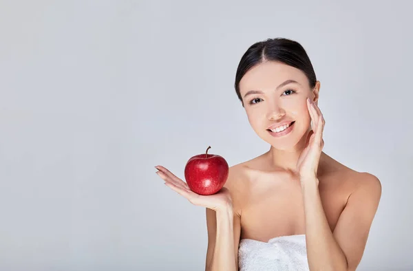 Un'immagine di una donna asiatica carina in un asciugamano bianco e una mela rossa . — Foto Stock