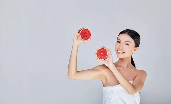 Dancing young Asian woman in a white towel with grapefruits. — Stok fotoğraf