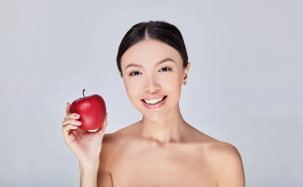 Portrait of a smiling Asian woman with a red apple. — ストック写真