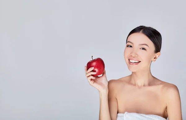 The cute Asian woman smiles with a red apple in his hand, isolate on a gray background. — 스톡 사진