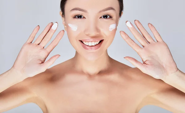 Primer plano de la joven mujer asiática feliz pone la crema con los dedos . —  Fotos de Stock