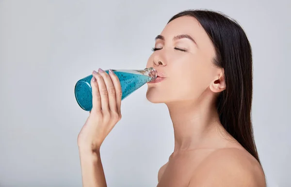 A close-up, Sensual Asian woman drinks detox cocktail after spa treatments. — Stock Photo, Image