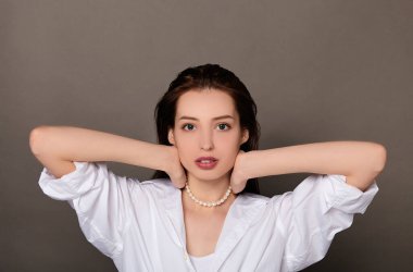 Beautiful young woman with wet hair puts on pearl beads.