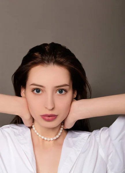 Close-up, una encantadora joven con el pelo mojado se pone cuentas de perlas . — Foto de Stock