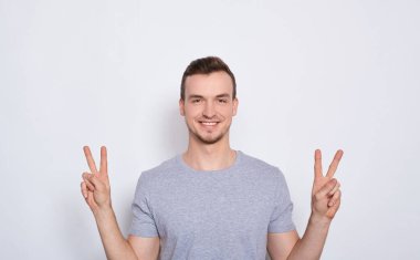Mutlu bir genç adam barış işareti gösterir..