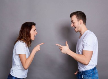 Genç ve güzel bir çift, gri bir arkaplanda birbirlerine bağırıyorlar..