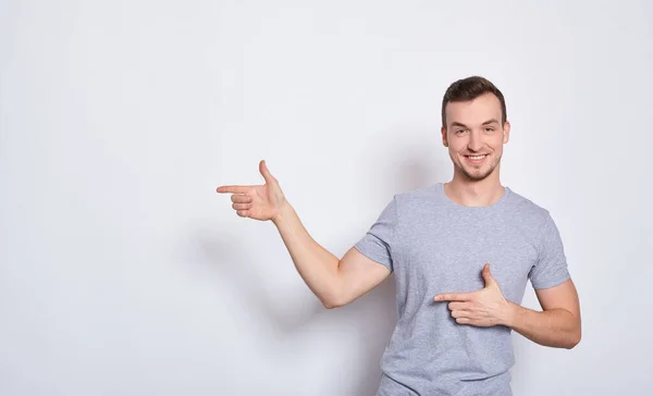 Un chico deportivo sonriente muestra sus dedos a la izquierda . — Foto de Stock