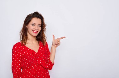 Yakın plan, kızıl dudaklı, tatlı, kahverengi saçlı, kırmızı elbiseli, beyaz arka planda izole edilmiş, kar beyazı bir gülümsemesi olan genç ve seksi bir kadın. Boşluğu kopyala.