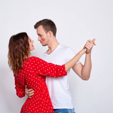 Uzun bir çerçeve, beyaz bir arka planda duran zarif giysiler içinde genç ve güzel beyaz bir çift..