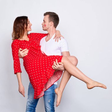 Uzun bir çerçeve, beyaz bir arka planda dururken sevgilisini kollarında tutarak zarif giysiler içinde dans eden güzel beyaz bir çift..