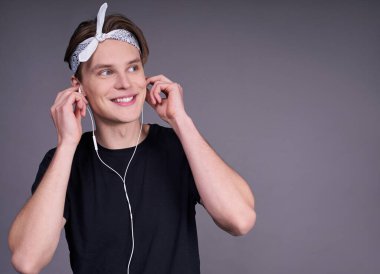 Sakin, beyaz bir adamdan etkilendim, bir öğrenci, siyah, temel tişörtlü, kulaklıkla müzik dinleyen, rüyasında sağa bakan, gri bir arka planda ezilmiş. Boşluğun bir kopyası.