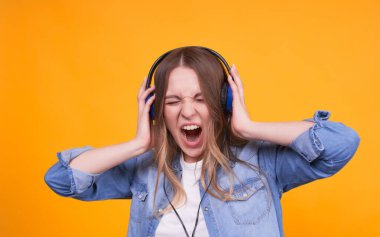 Sıradan kıyafetler içinde, kulaklıkla müzik dinlemekten, çığlık atmaktan, sarı arka planda şarkı söylemekten mutlu bir kızın portresi. Kulaklıkla müzik dinleyen öğrenci gözleri kapalı, izole bir şekilde..