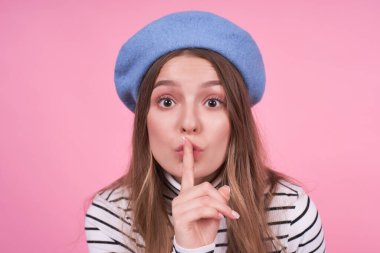 Şapkalı, sevimli, çekici bir kızın portresi. Sessiz, işaret parmağında dudak bükme işareti var. Sessiz ol ya da kimseye söyleme..