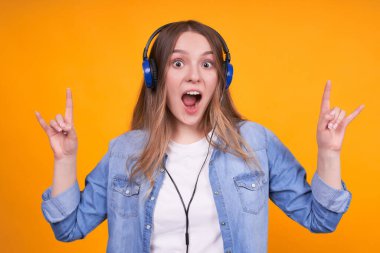 Sarışın, güzel, beyaz bir kadın izole edilmiş arka planda çılgınca bir ifadeyle bağırıyor ve elleri havada bir kaya sembolü yapıyor. Müzik yıldızı. Ağır konsept.