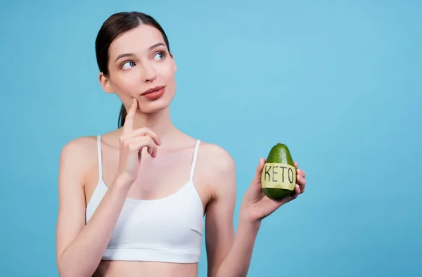 Pensive Attractive Pretty Young Sports Girl White Top Holding Avocado — Stock Photo, Image
