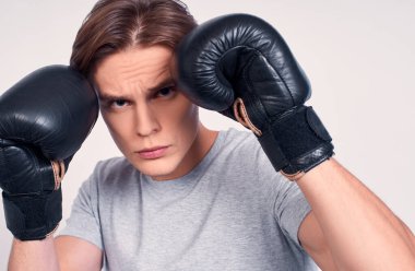 Genç fitness sporcusu, saç bandı tişörtlü boksör hafta sonunu evde, beyaz arka planda yalnız geçirir. Spor motivasyonu konsepti. Boks eldivenleriyle boks egzersizleri yapıyor..