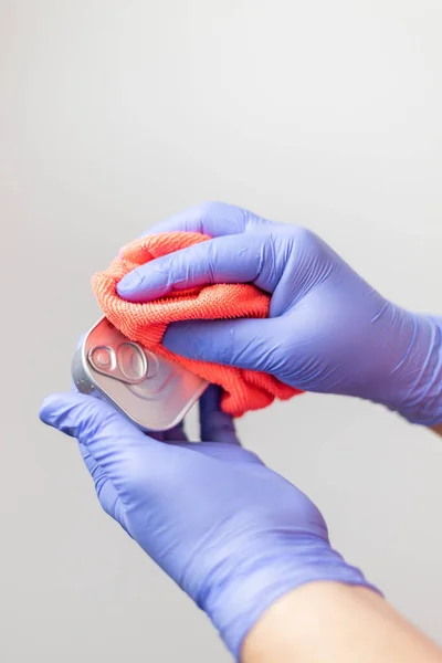 Eldivenli eller, bakkal alışverişinden sonra konserve kutusunu temizliyor. Koronavirüsün yayılmasını önlemek için.