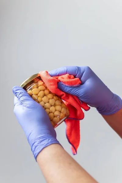 Eldivenli eller, bakkal alışverişinden sonra konserve kutusunu temizliyor. Koronavirüsün yayılmasını önlemek için.