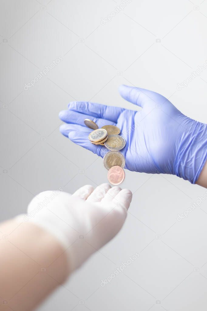 gloved hand offering a few euro coins. Concept of financial crisis after the coronavirus (covid19)