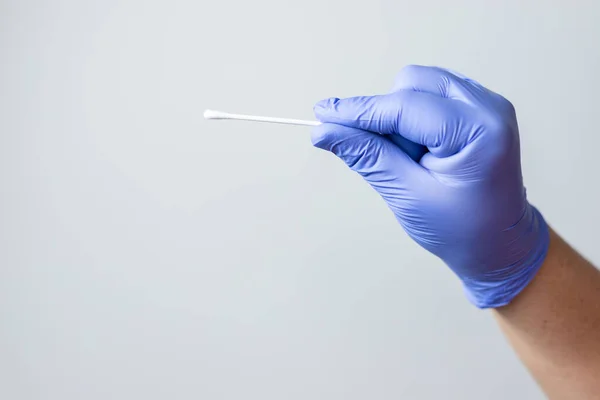 Mavi eldivenli el, Coronavirus geniz test çubuğu ya da Coperid-19 'u tutuyor. Coronavirus test konsepti.