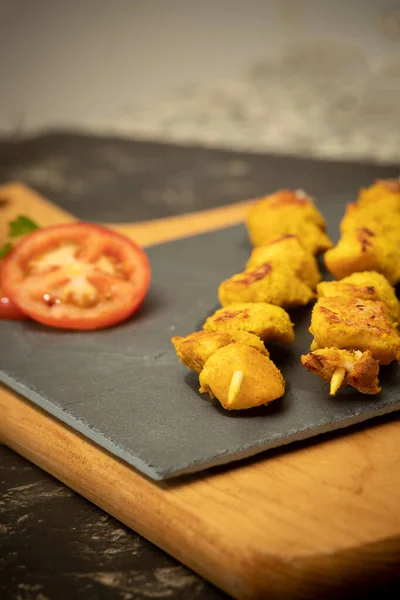 Siyah taşın üzerinde Fas şişleri ve domates dilimli ahşap kesme tahtaları.