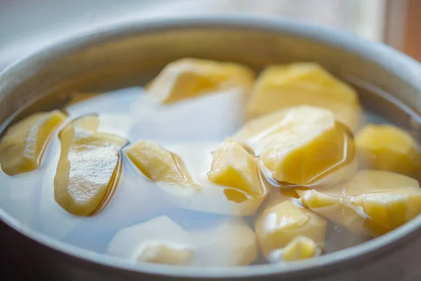 Bir tencere suda patates soymak.