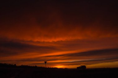 Gün batımında arka planda bir arabanın dış çizgisi, kırmızı gökyüzü