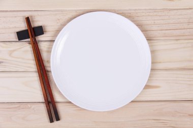 Ahşap arka plan üzerinde beyaz boş plaka ve suşi chopsticks