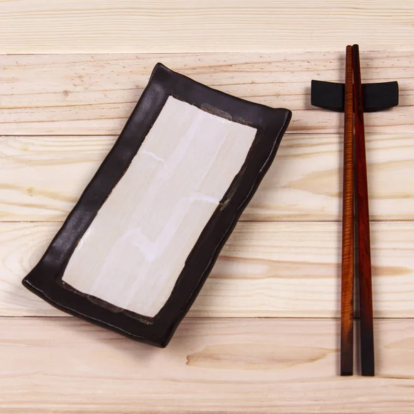 Leerer Teller und Sushi-Stäbchen auf Holztisch — Stockfoto