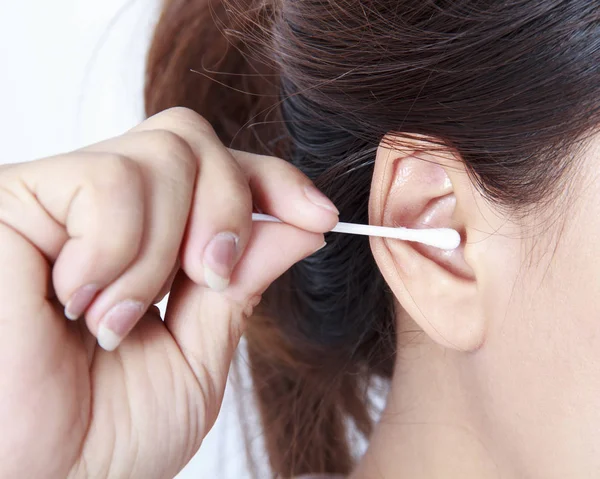 Vrouwelijke schoonmaak oor met wattenstaafje op witte achtergrond. Rechtenvrije Stockfoto's