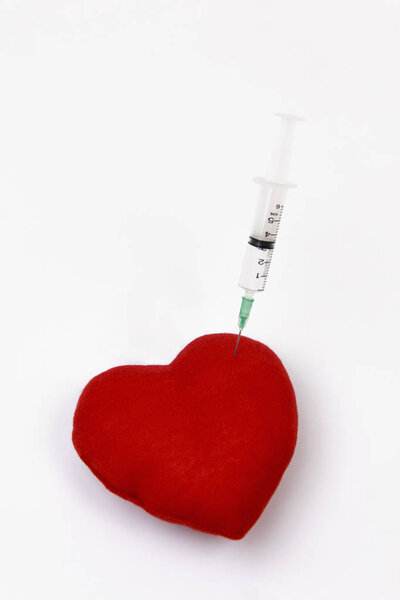 Шприц, вводящий красное сердце на белом фоне
