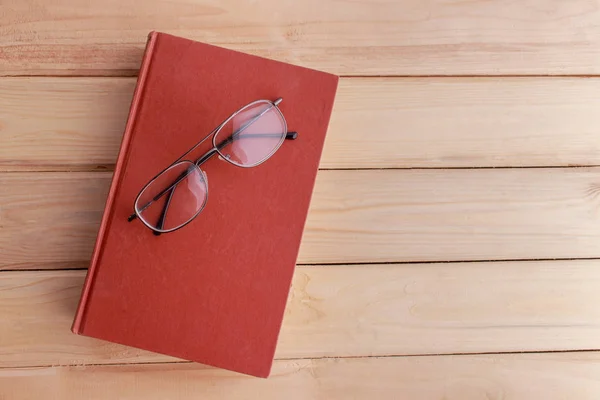 Kniha a brýle na dřevěné podlaze pro pozadí. — Stock fotografie