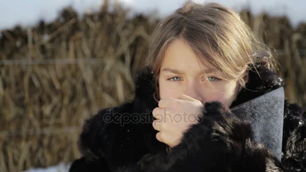 Porträtt av en norra pojke på nära håll med en yxa. Teen pojke i vinterrock med en yxa. Sibiriska pojke med aktern ansikte. — Stockvideo