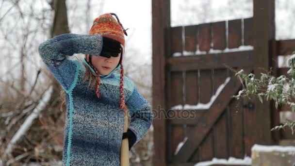 Boy removes snow shovel near the house. Cleaning snow in the winter near the house. The child cleans shovel the snow covered track. — Stock Video