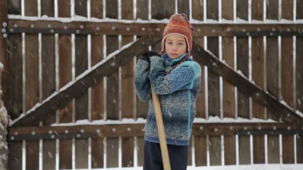Boy removes snow shovel near the house. Cleaning snow in the winter near the house. The child cleans shovel the snow covered track. — Stock Video