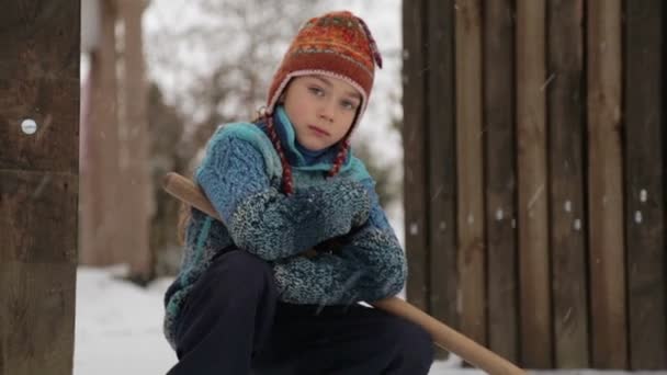 Boy removes snow shovel near the house. Cleaning snow in the winter near the house. The child cleans shovel the snow covered track. — Stock Video